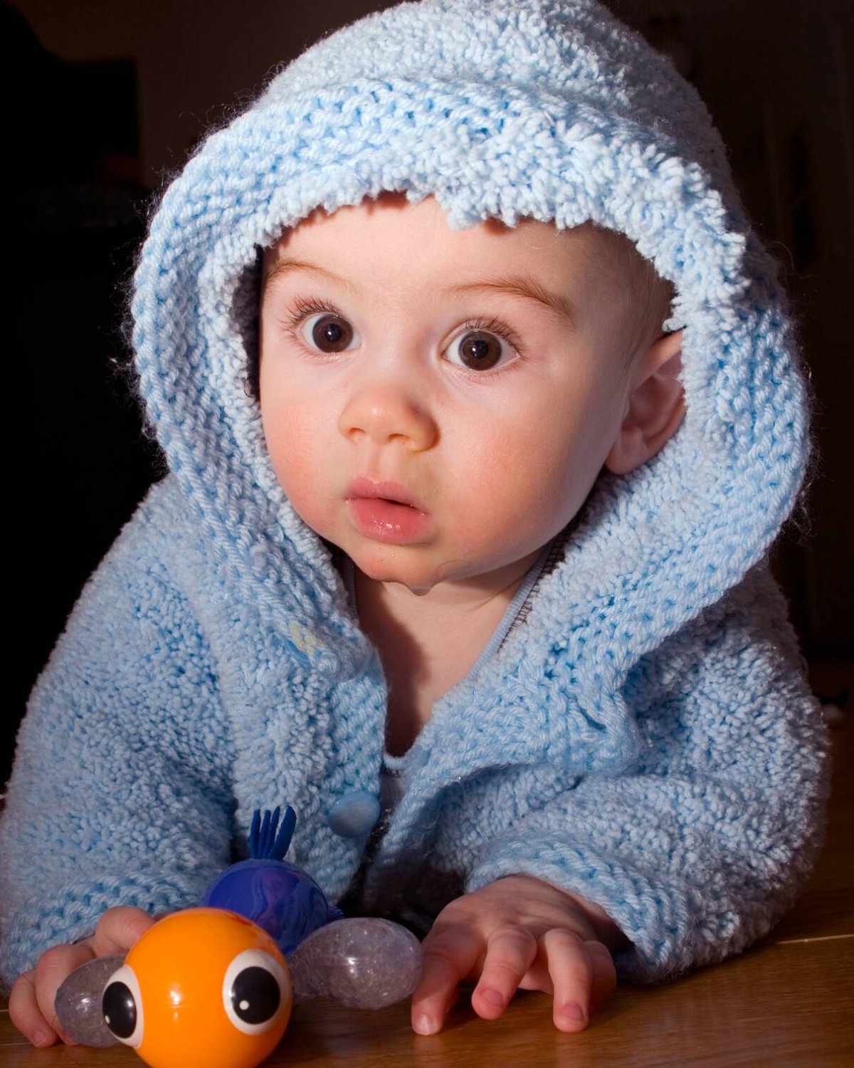 a baby with his bumblebee rattle. Bot the baby and the toy have big round eyes.